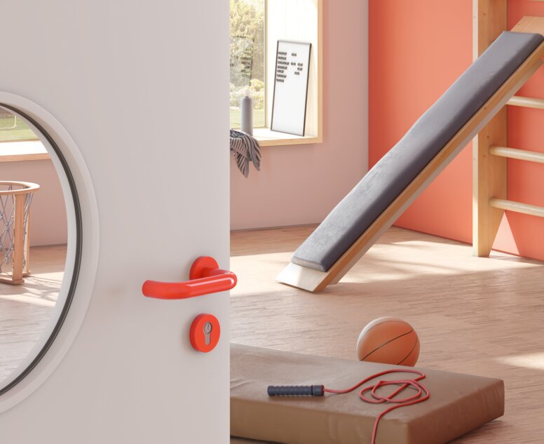 Tür zu einem Sportraum eines Kindergartens ausgestattet mit einem Türdrücker in der Farbe Orange aus Polyamid