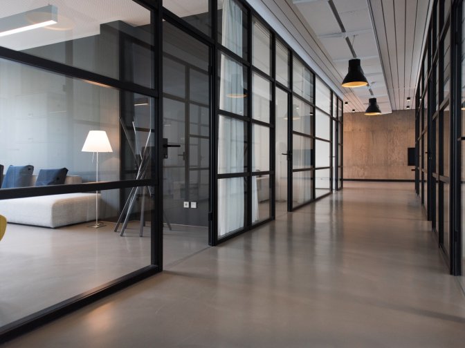 Gang in einem Bürogebäude mit transparenten Türen zu verschiedenen Büros
