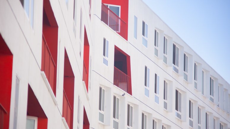 Weiß gestaltete Außenfassade eines Pflegeheims mit vereinzelten rot gestrichenen Fensterwänden